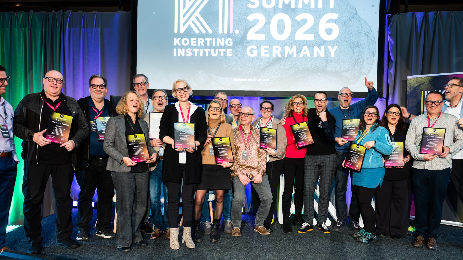 Groupe de formateurs certifiés tenant des certificats sur scène au KI Summit 2026 en Allemagne